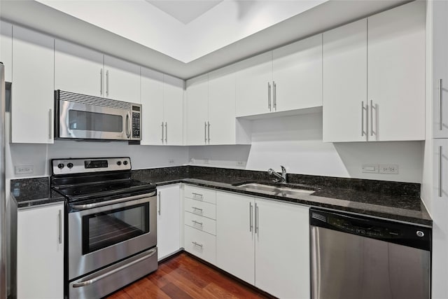 54 Rainey St Unit 613, Austin, TX 78701 - kitchen featuring appliances with stainless steel finishes, a sink, white cabinets, and dark stone counters