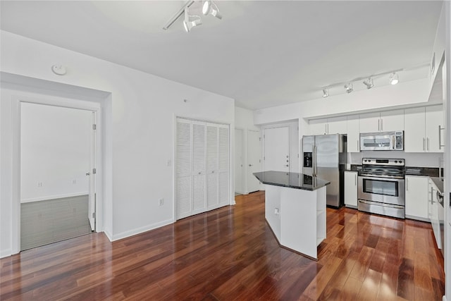 kitchen with white cabinets, stainless steel appliances, a kitchen island, and dark wood-type flooring