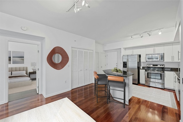 54 Rainey St Unit 613, Austin, TX 78701 - kitchen featuring appliances with stainless steel finishes, dark countertops, rail lighting, and a kitchen island