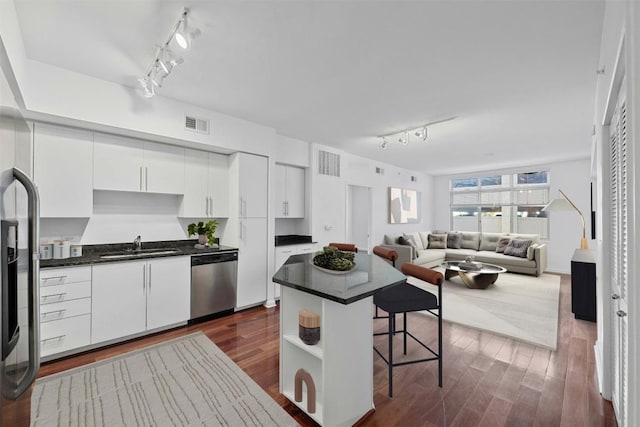 54 Rainey St Unit 613, Austin, TX 78701 - kitchen with stainless steel appliances, track lighting, a breakfast bar, dark countertops, and white cabinetry