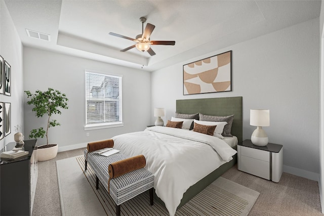 bedroom with a tray ceiling, ceiling fan, and light colored carpet