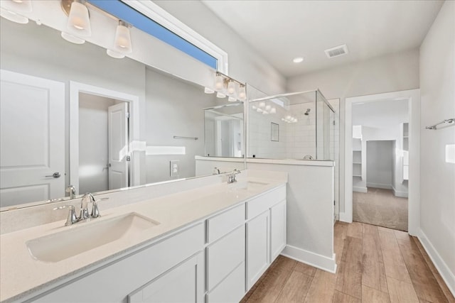 bathroom with walk in shower, vanity, and hardwood / wood-style flooring