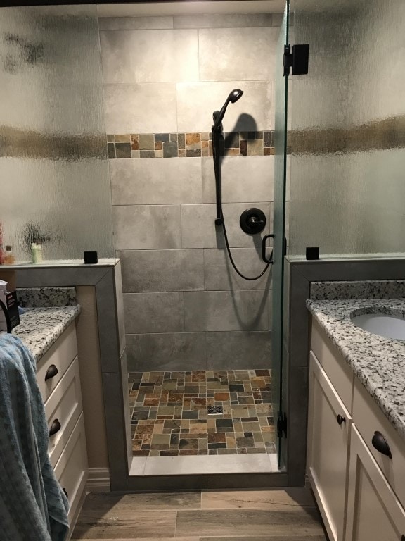 bathroom featuring hardwood / wood-style flooring, vanity, and a shower with shower door