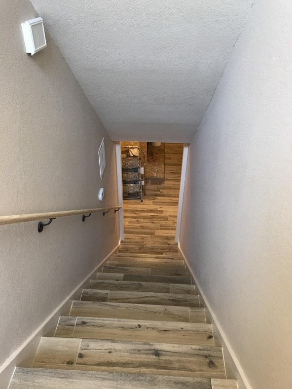 stairway featuring hardwood / wood-style flooring and a textured ceiling