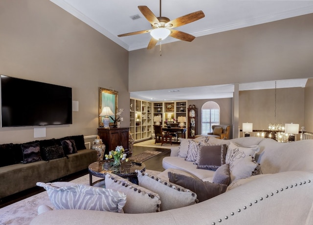 living room with hardwood / wood-style floors, a towering ceiling, ceiling fan with notable chandelier, and ornamental molding