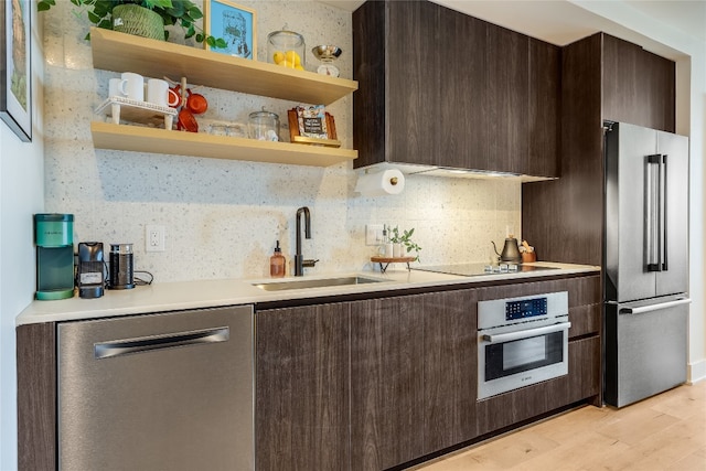 kitchen featuring sink, decorative backsplash, appliances with stainless steel finishes, dark brown cabinets, and light hardwood / wood-style floors