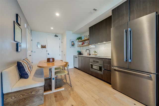 kitchen featuring backsplash, stainless steel appliances, light hardwood / wood-style floors, and sink