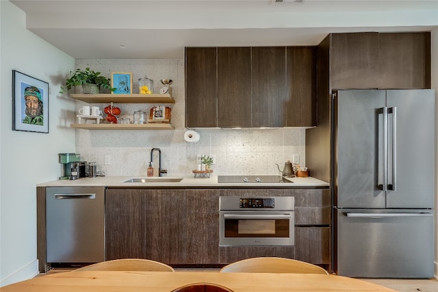 kitchen featuring dark brown cabinetry, stainless steel appliances, backsplash, and sink