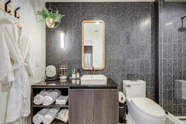 bathroom with vanity, a shower, backsplash, toilet, and tile walls