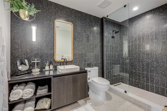 bathroom featuring backsplash, a tile shower, vanity, tile walls, and toilet