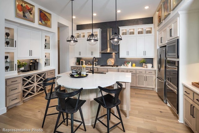 kitchen featuring white cabinets, wall chimney range hood, and appliances with stainless steel finishes