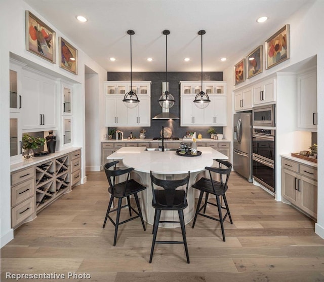 kitchen featuring pendant lighting, a center island with sink, white cabinets, and stainless steel appliances