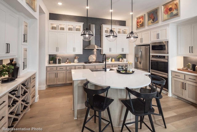 kitchen with a center island with sink, white cabinets, hanging light fixtures, and appliances with stainless steel finishes