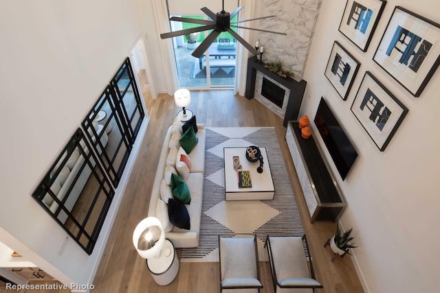 living room featuring hardwood / wood-style floors, ceiling fan, and a high ceiling