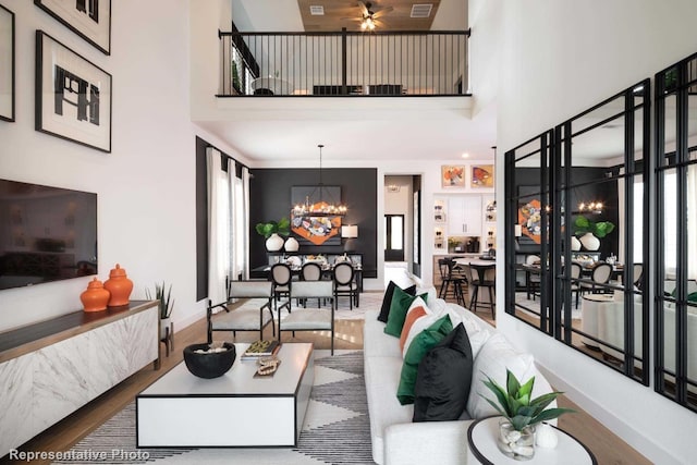 living room with a high ceiling, ceiling fan with notable chandelier, and hardwood / wood-style flooring