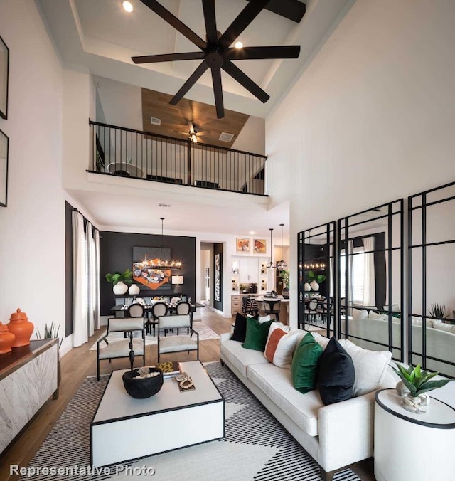 living room featuring hardwood / wood-style floors, ceiling fan with notable chandelier, and high vaulted ceiling