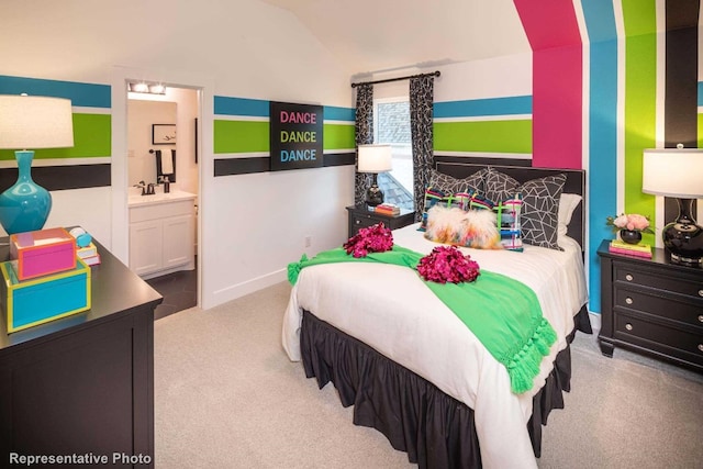 bedroom featuring ensuite bath, light carpet, sink, and lofted ceiling