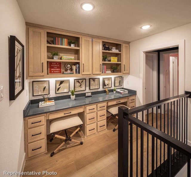 office with light hardwood / wood-style floors, built in desk, and a textured ceiling