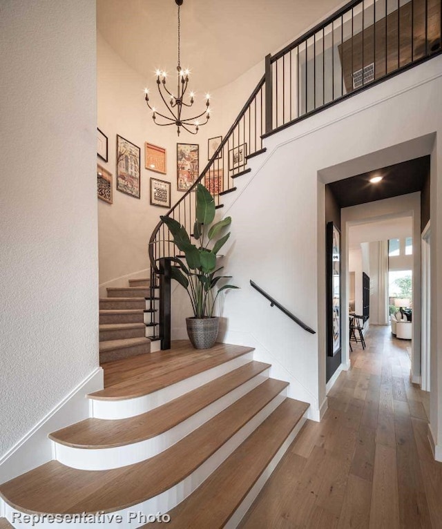 stairs with a chandelier and hardwood / wood-style flooring