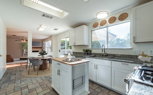 kitchen with white cabinets, ceiling fan, stove, and sink