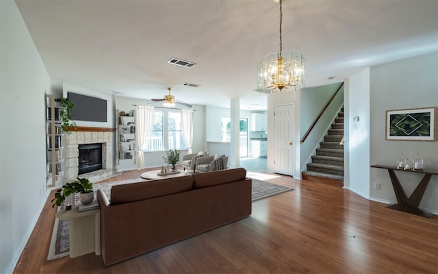 living room with hardwood / wood-style floors, ceiling fan with notable chandelier, and a fireplace