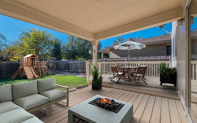 deck featuring a yard, a playground, and an outdoor living space with a fire pit