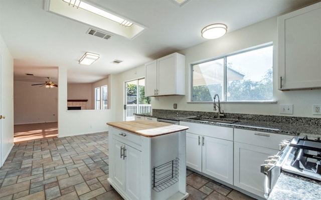 kitchen with stove, white cabinetry, and sink