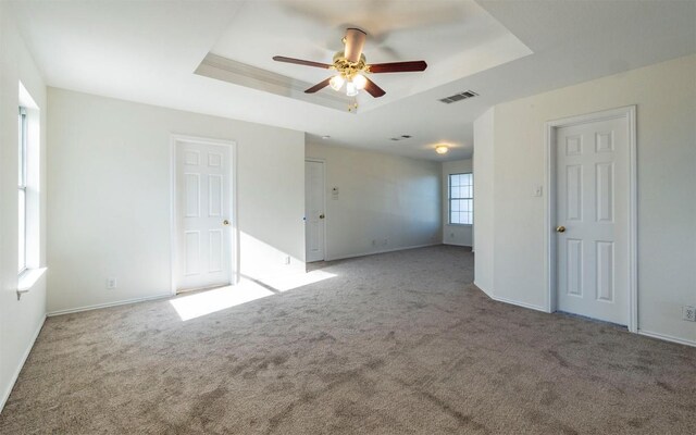 carpeted empty room with ceiling fan and a tray ceiling