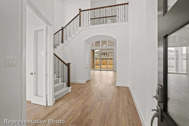 foyer entrance featuring light wood-type flooring and a towering ceiling