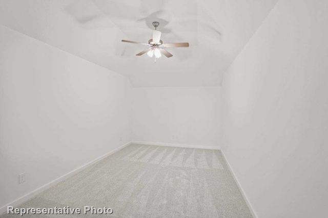 carpeted spare room with ceiling fan and vaulted ceiling