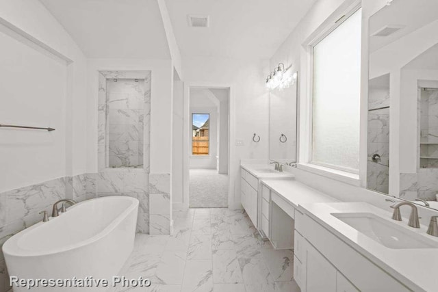 bathroom featuring vanity, a tub to relax in, vaulted ceiling, and tile walls