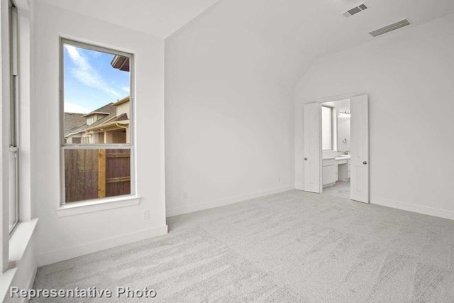 unfurnished room with light colored carpet and lofted ceiling