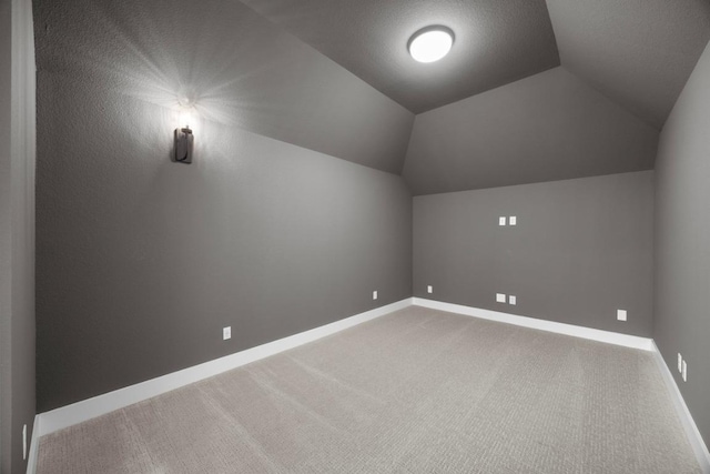 additional living space with baseboards, vaulted ceiling, and carpet floors