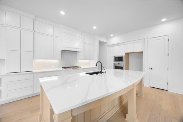 kitchen featuring custom exhaust hood, light wood-type flooring, a sink, and appliances with stainless steel finishes