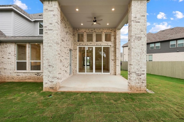 back of house with ceiling fan, a lawn, a patio area, fence, and brick siding