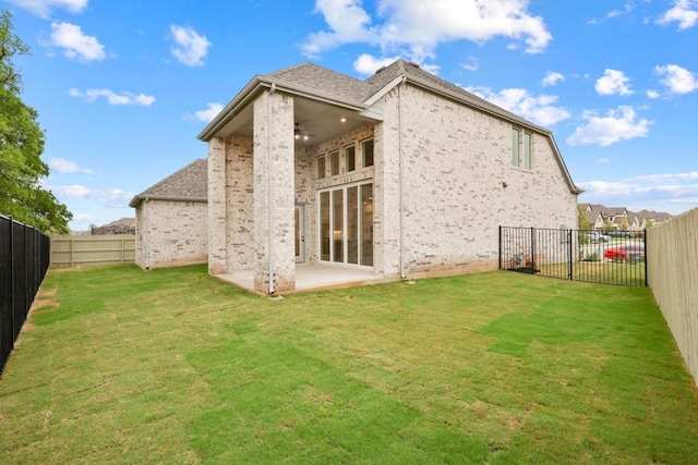 rear view of property featuring a yard, a fenced backyard, a ceiling fan, a patio area, and brick siding