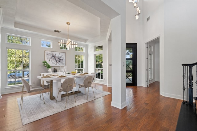 dining room with a notable chandelier, dark hardwood / wood-style floors, and a raised ceiling