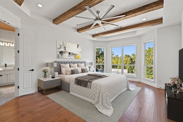 bedroom featuring beamed ceiling, connected bathroom, hardwood / wood-style flooring, and ceiling fan