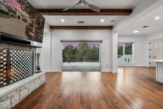 unfurnished living room featuring beamed ceiling, wood-type flooring, and ceiling fan