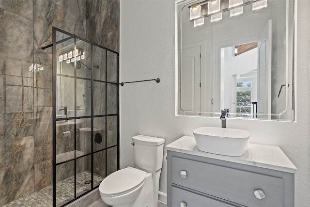 bathroom with a tile shower, vanity, and toilet