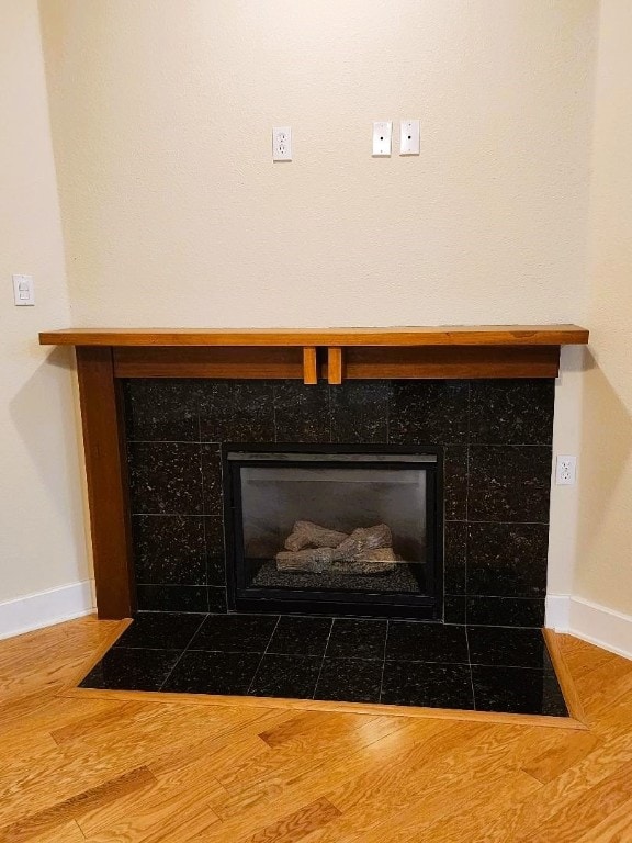 interior details with a tile fireplace and wood-type flooring