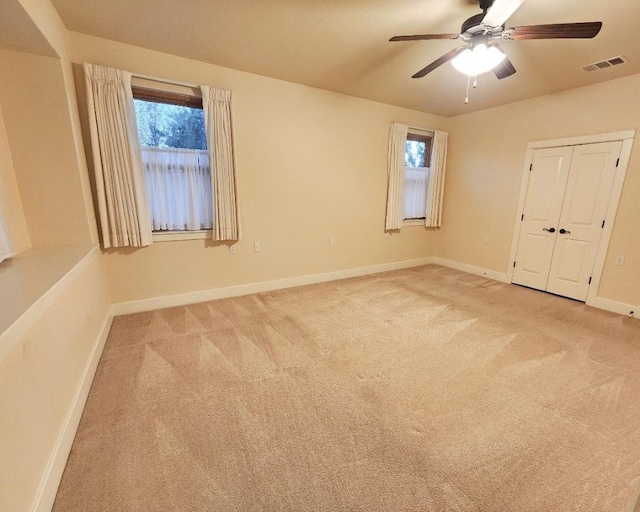 unfurnished bedroom with multiple windows, ceiling fan, a closet, and light carpet