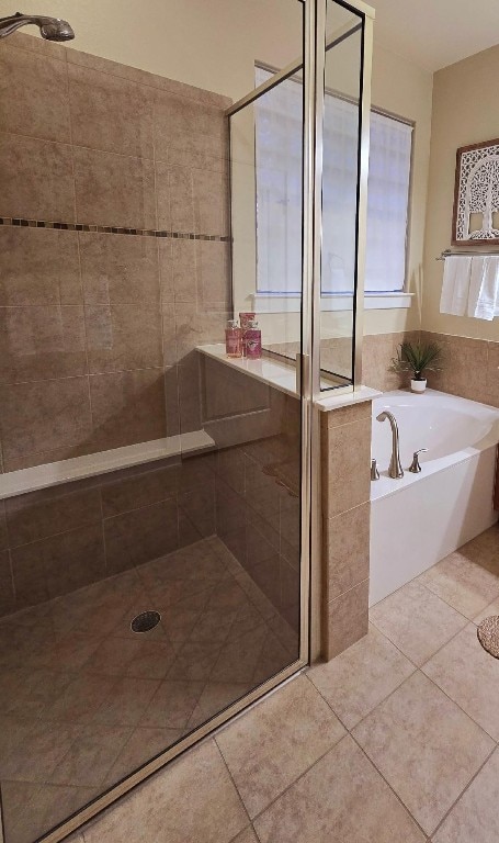 bathroom with a stall shower, tile patterned flooring, and a bath