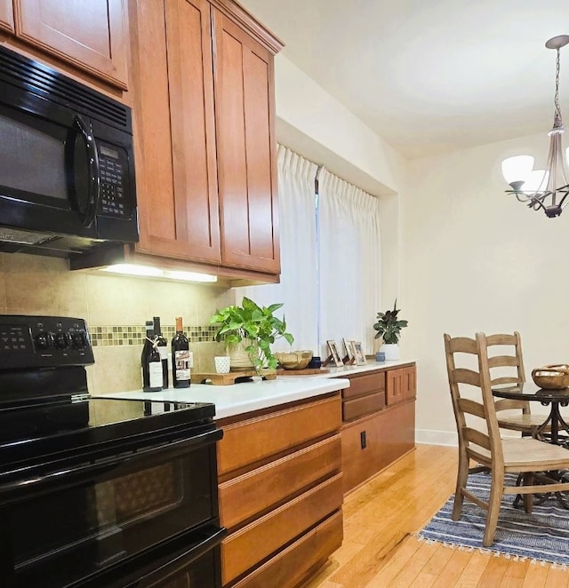 kitchen with a chandelier, light countertops, brown cabinets, black appliances, and pendant lighting