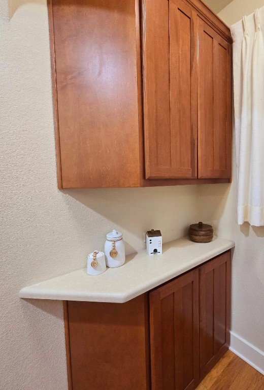 kitchen featuring baseboards, light countertops, light wood-style flooring, and brown cabinets