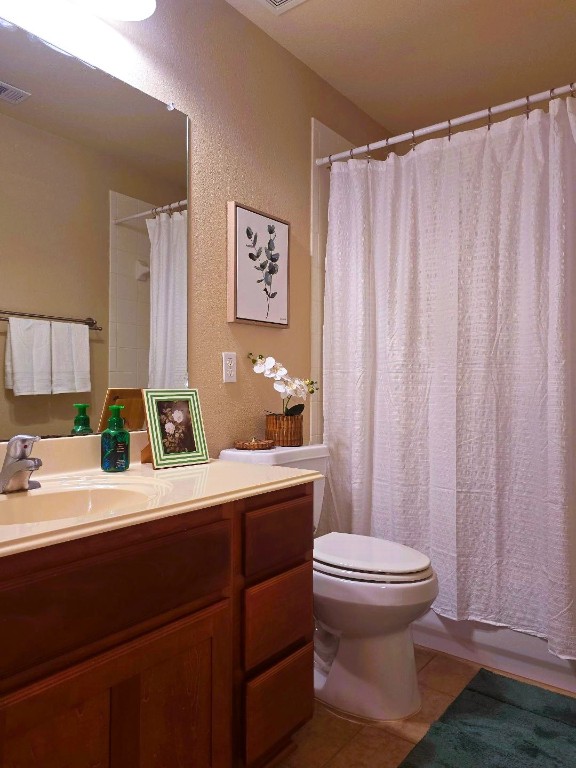 bathroom featuring a textured wall, toilet, vanity, visible vents, and tile patterned floors