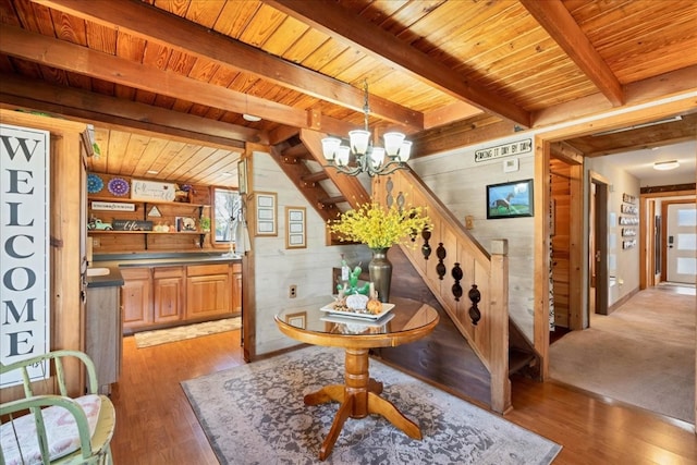 dining space featuring a notable chandelier, beam ceiling, light wood-type flooring, and wooden ceiling