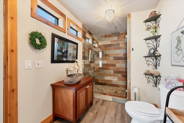 interior space with vanity, hardwood / wood-style flooring, toilet, a shower with shower door, and a chandelier