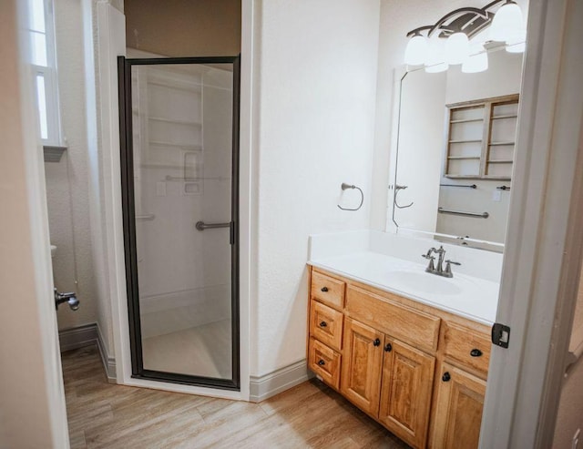 bathroom with a stall shower, wood finished floors, vanity, and baseboards