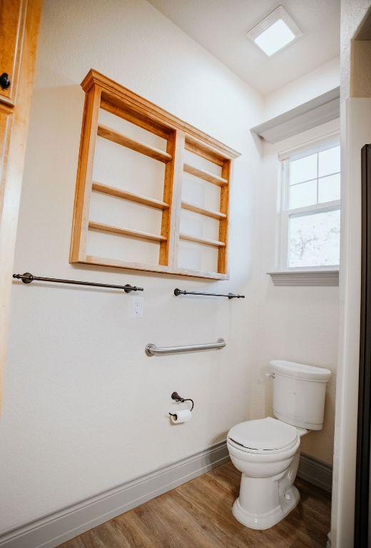 bathroom with toilet, baseboards, and wood finished floors